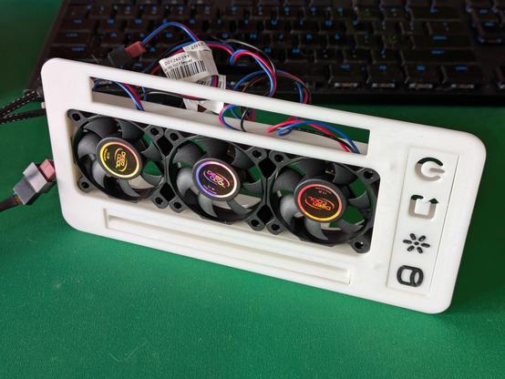 A photo of the front panel of a 3D printed computer case. The front is dominated by a large rectangular opening with three cooling fans in a row. The colourful, reflective stickers on the fans say "Deep Cool". A mess of blue, red and black wires are dangling off the back of the panel.