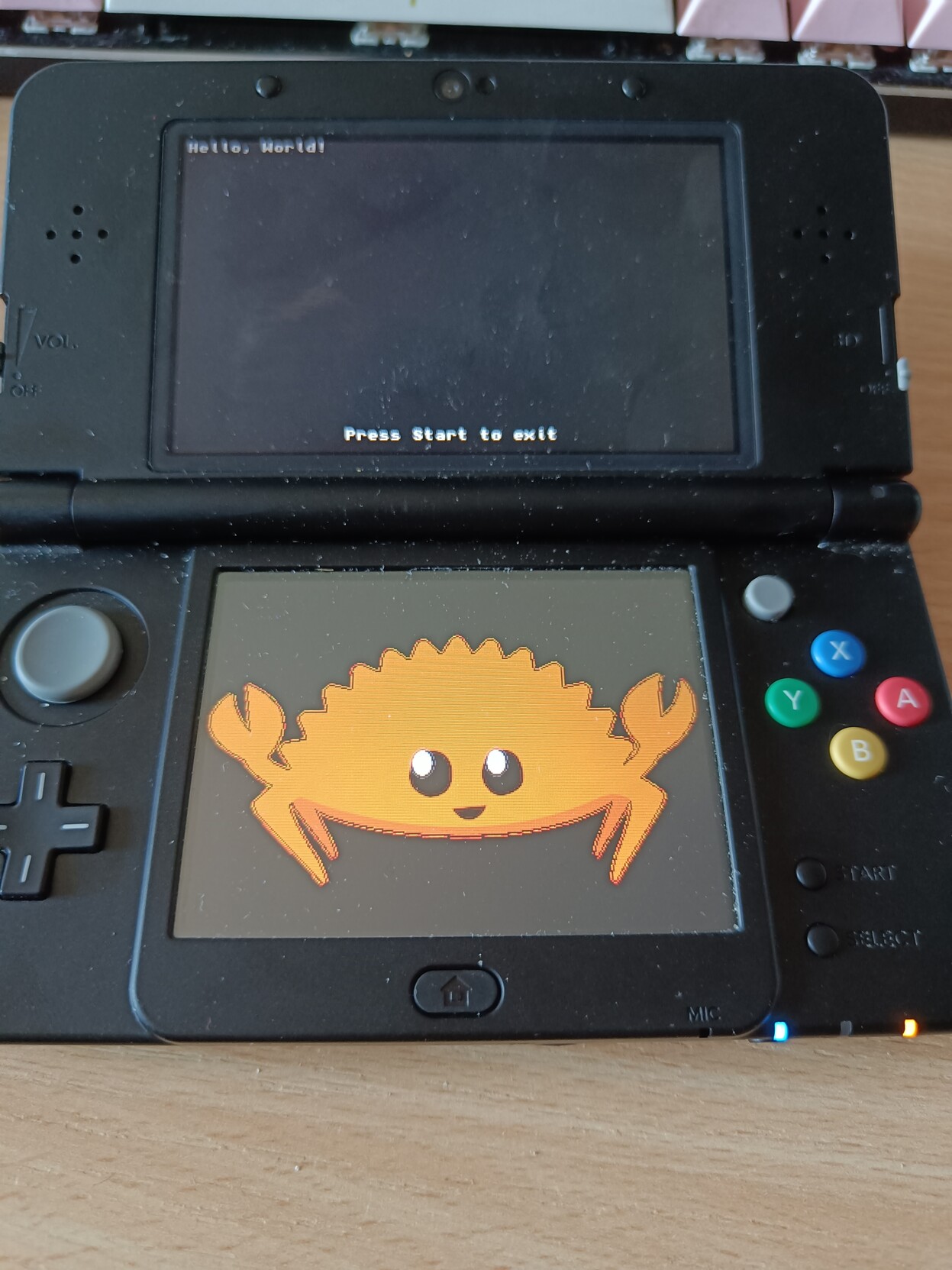 nintendo 3ds showing "hello world" on the top screen and ferris the crab on the bottom screen 