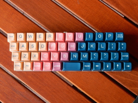 A Zlant keyboard (designed by Ziptyze and sold by 1UpKeyboards) with SA Vilebloom as keycap set.

The keyboard has a uniform stagger, i.e. every row of keys has an offset of ¼ key width to the next row, hence filling the gap between ortholinear and classic staggered keyboard layouts.

It's a keyboard just consisting of three layers of white PCB material, but it has no frame so you nearly don't see anything of it in this top-down shot.

The keycaps show a (stepped) gradient slanted in the opposi…