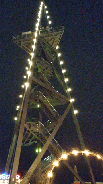 Der Aussichtsturm auf dem Uetliberg vom Fuß aus nach oben fotografiert, bei Nacht und beleuchtet. Er sieht ein bisschen aus wie beleuchtete Weihnachtsdeko.