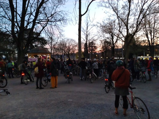Hunderte Leute mit Velo warten leichtem Abendrot auf einem Platz mit ein paar wenigen Bäumen darauf auf den Beginn der Demo.