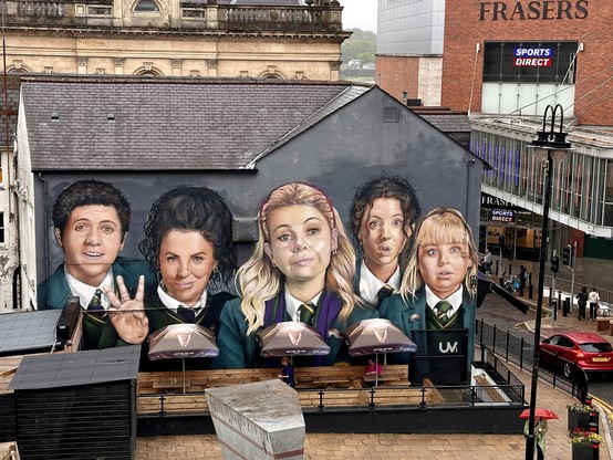 Großes Wandgemälde in (London)derry das die Wand eines zweistöckigen Hauses in fast voller Höhe einnimmt. Dargestellt sind die fünf Teenager-Hauptcharaktere aus Derry Girls: James, Michelle, Erin, Orla, Clare