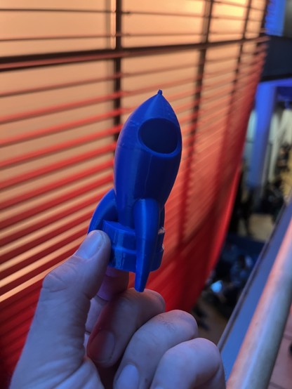 Foto einer 3D, gedruckten Fairydust, aus blauem Filament vor einem orangenen Hintergrund