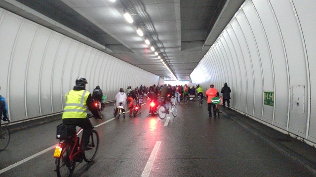 The end of the crowd in the Tunnelstrasse tunnel. Left a guy on a red s-pedelec (with yellow number plate), black rain cloths and a yellow hi-viz safety vest.