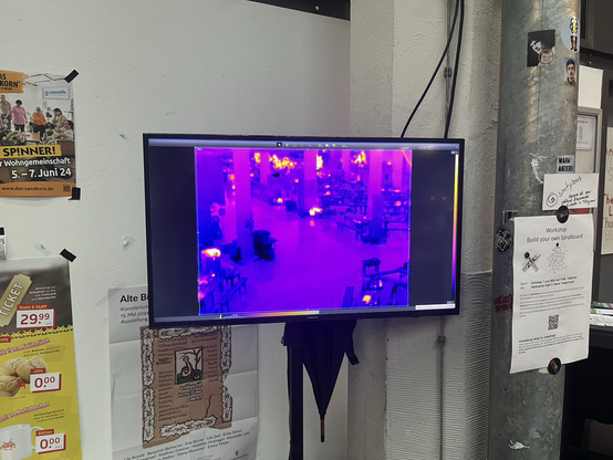 Wärmebild auf großem Monitor, komplett blau und lila, Atrium des ZKM von oben aufgenommen voller GPN Tischen