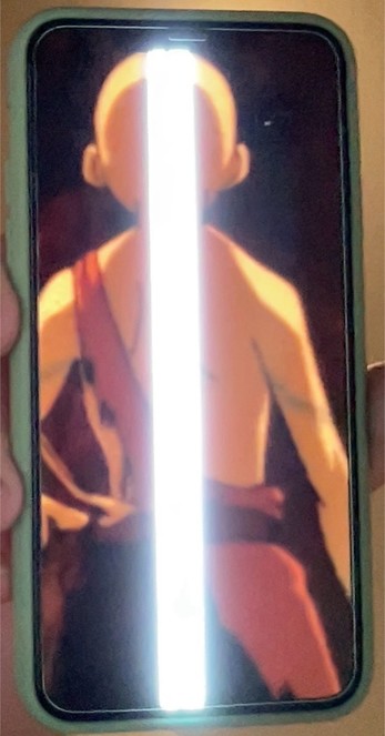 A photo of me holding an iPhone that shows a picture of Aang, from Avatar The Last Airbender. Right where his stripe tattoo should be in the center of his back, the phone has a screen fault that is showing as a 1cm wide vertical beam of intensely bright white.