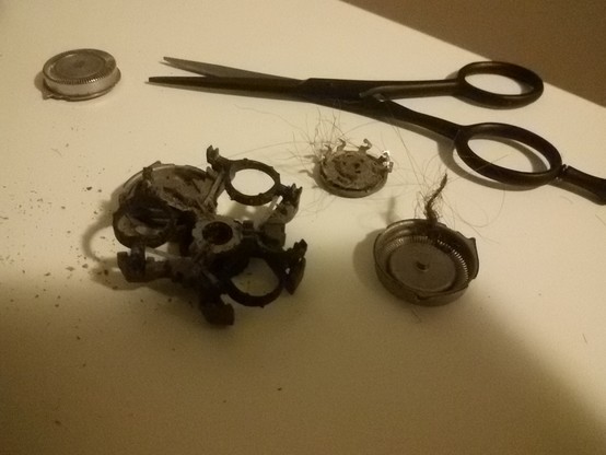 disassembled beard trimmer with a bunch of hair stuck in it after being cut off
