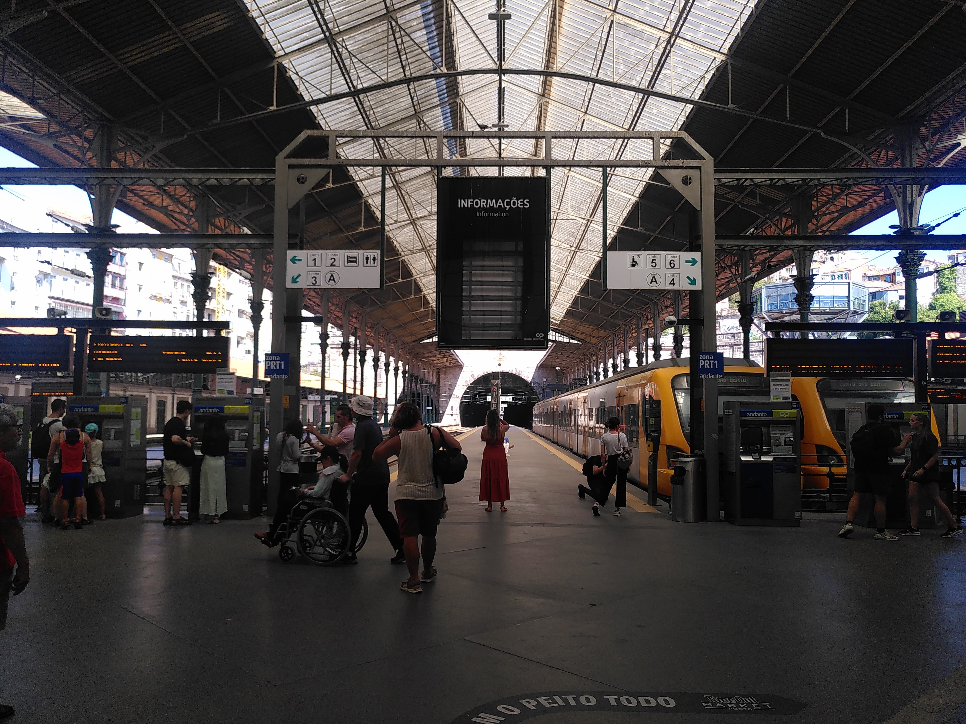 Abfahrtshalle mit gelben Zügen. Zentralperspektive. Am Ende der Halle sieht man den Eingang in einen steinernen Tunnel durch den alle Züge fahren.