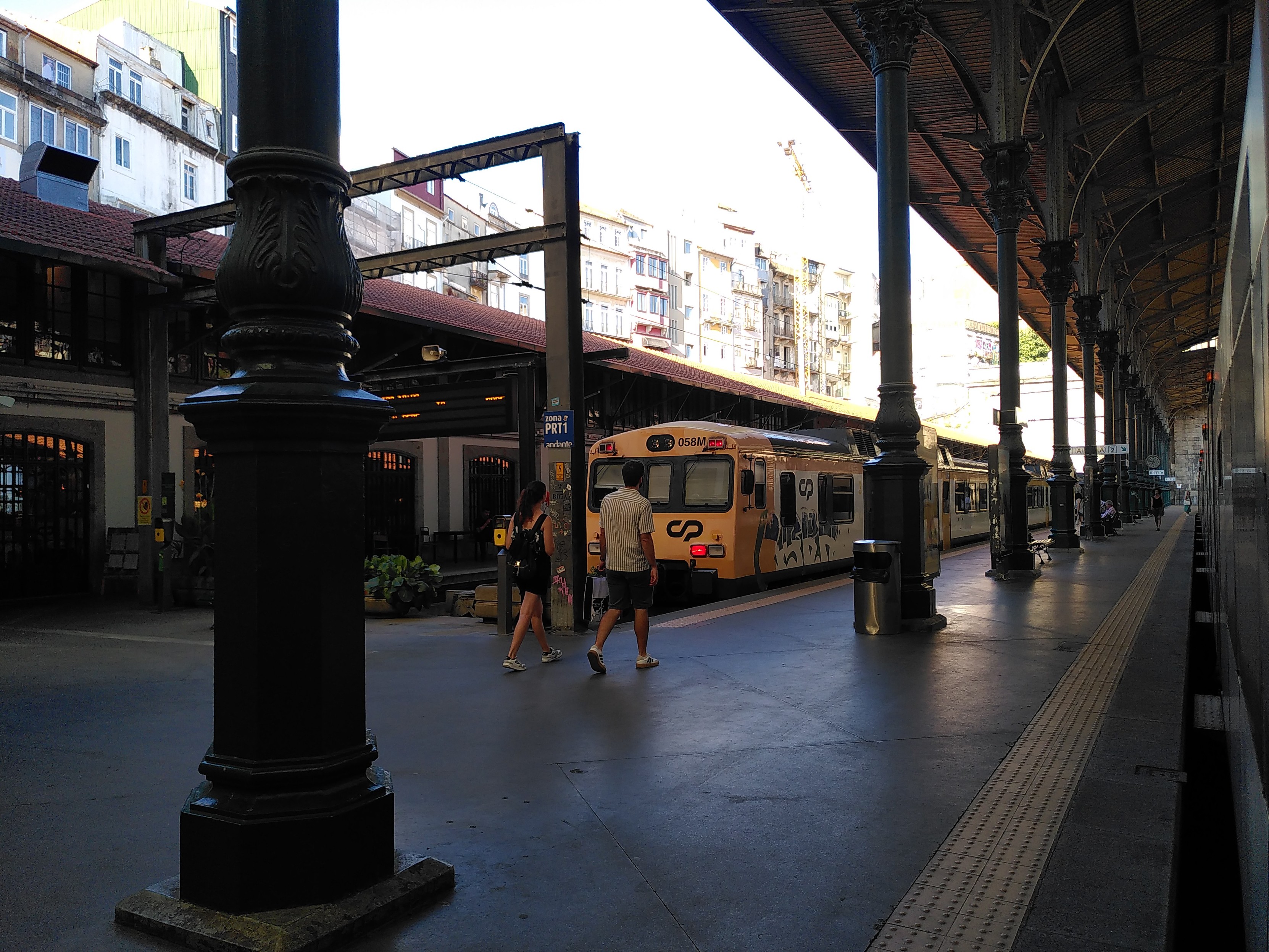 Blick auf ein Gleiß aus dem Zug. Man sieht die imposanten Stützen auf dem Bahnsteig stehen, über denen sich eine stählerne Dachkonstruktion auffächert.