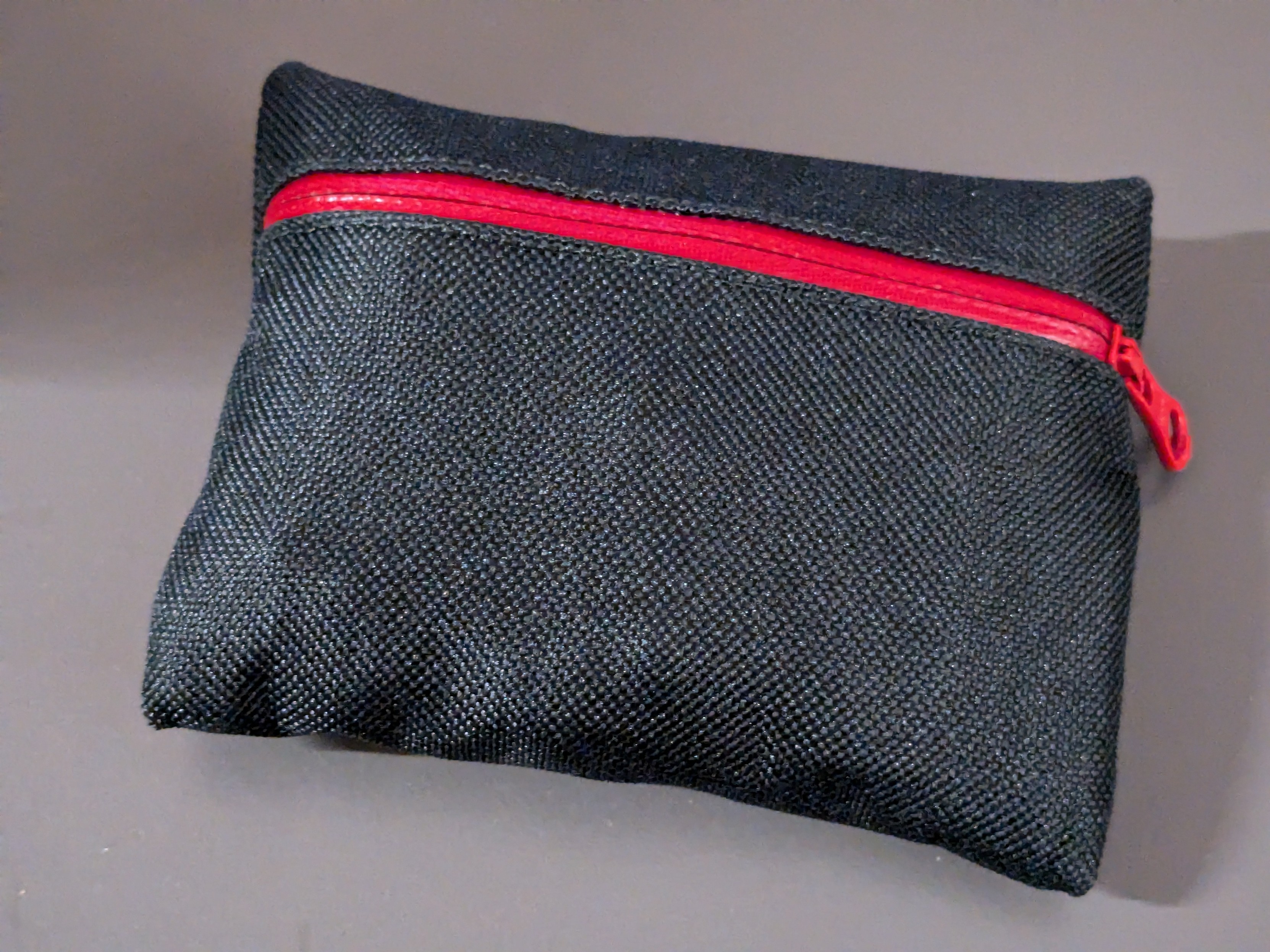 A black pouch with a red zipper.