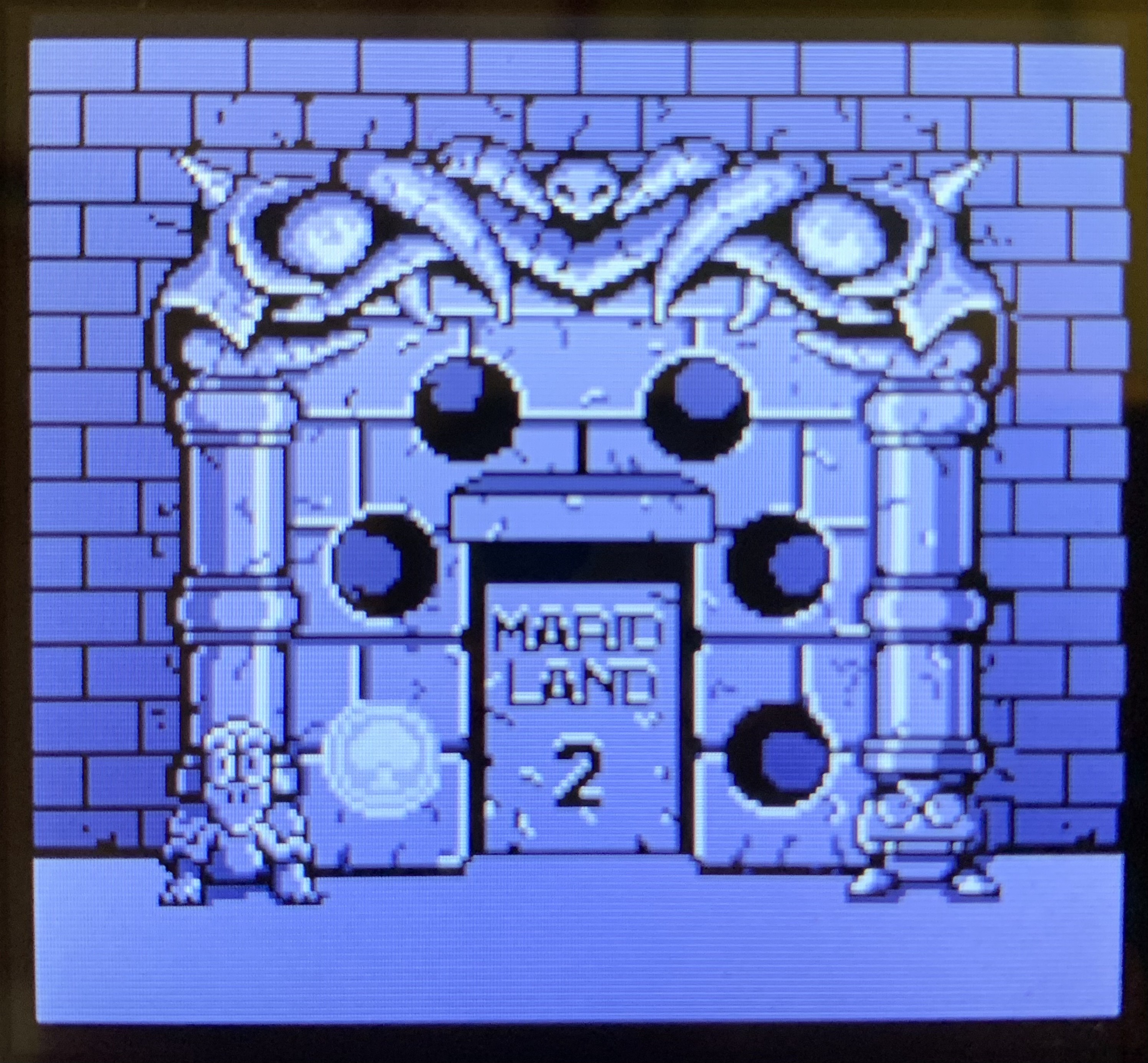 The first coin is inserted into the portal. 5 empty sockets surround the stone door labeled Mario Land 2