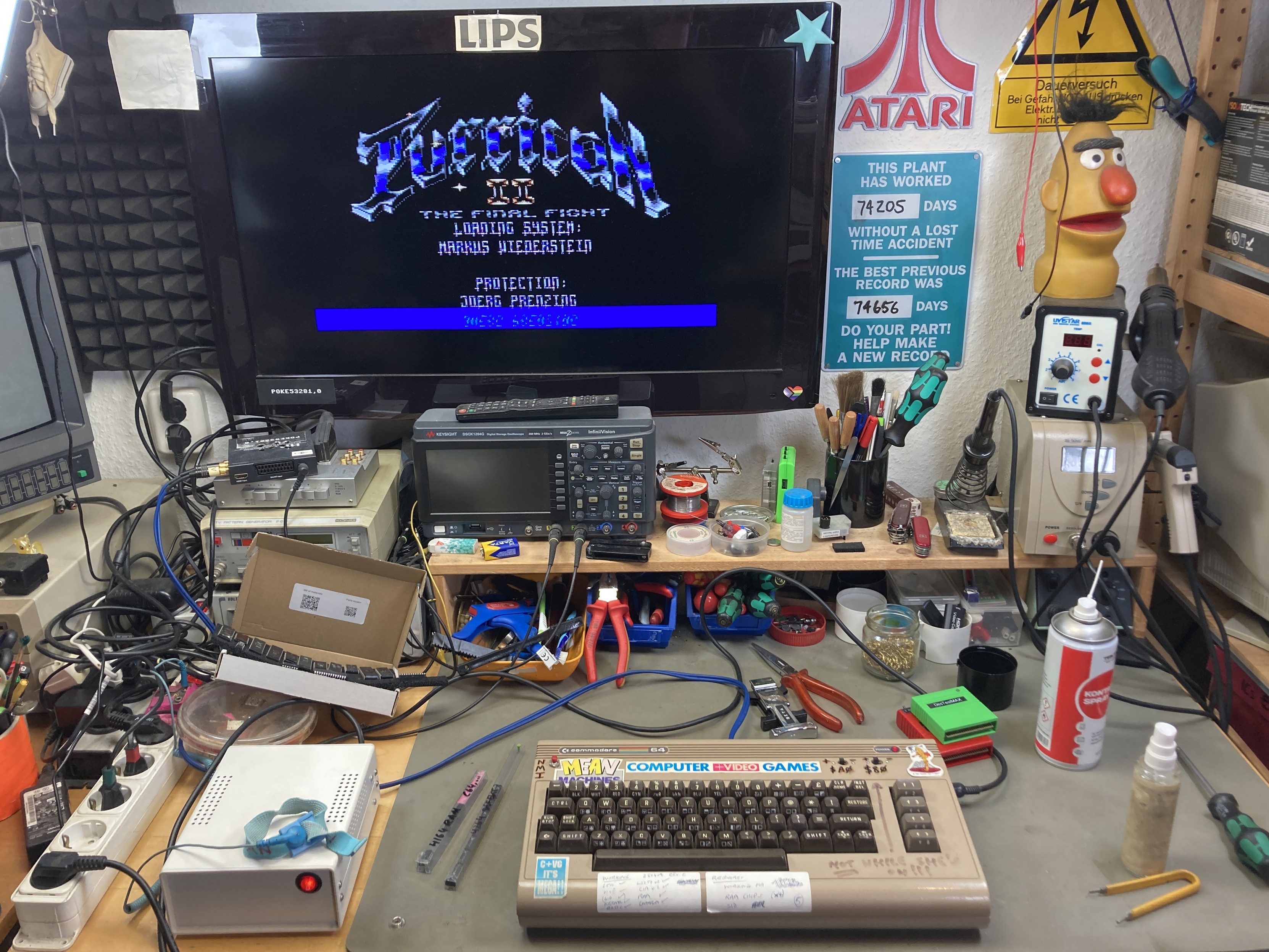 C64 covered in stickers on my workbench with the Turrican II game title screen showing on the monitor. Various tools are scattered on the desk. C64 covered in stickers on my workbench with the Turrican II game title screen showing on the monitor. Various tools are scattered on the desk.