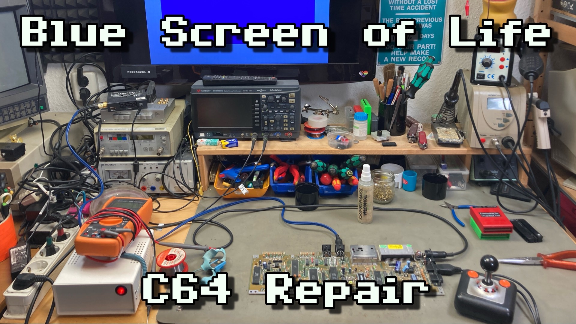 Thumbnail for my video, showing my workbench with a C64 board on in and several tools scattered around. In the background, the monitor shows the blue C64 BASIC screen. The overlayed text reads "Blue Screen of Life C64 Repair".