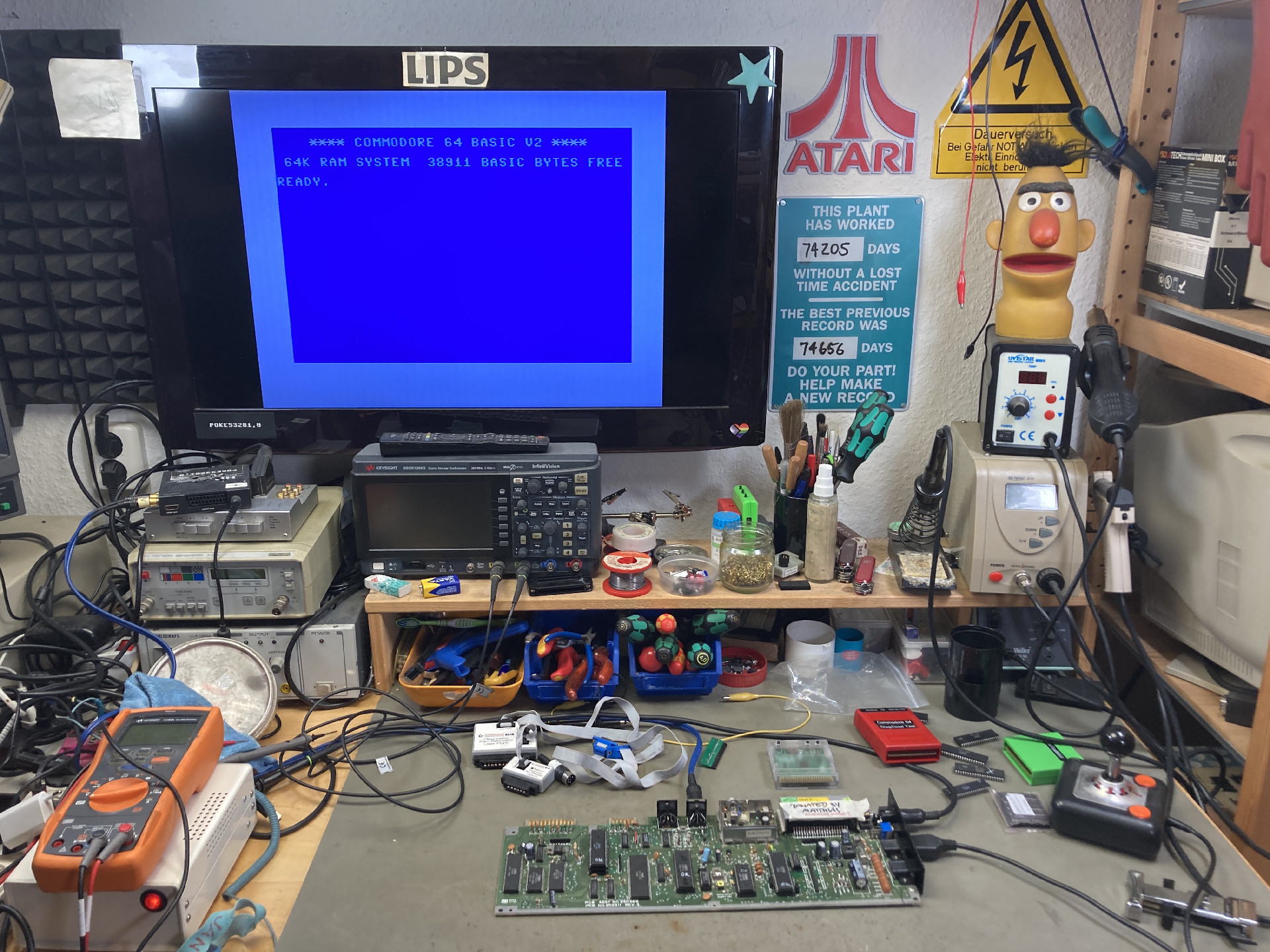 Commodore 64 board on my workbench with tools and Diagnostic cartridges scattered around. The monitor shows the blue BASIC startup screen after the successful repair.