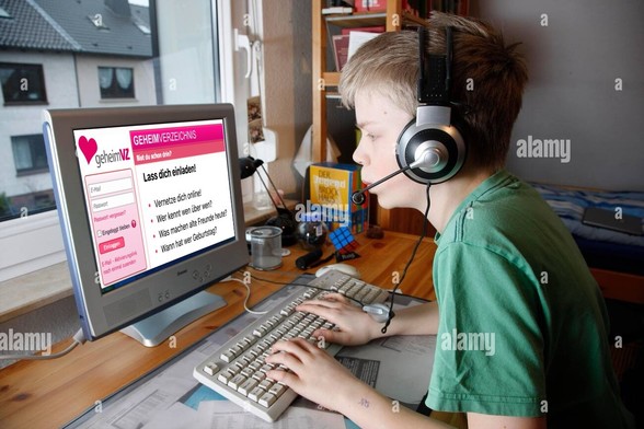 Ein Junge mit Headset sitzt am Schreibtisch und hat die Finger auf der Tastatur, auf seinem Monitor ist die Webseite „geheimVZ“ im Design von schülerVZ zu sehen