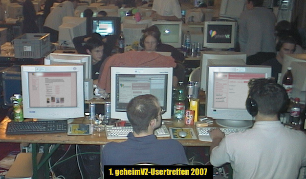 Ein alt wirkendes Foto von vielen Menschen in einem Raum mit Computern und Eisteeflaaschen und Röhrenmonitoren auf denen das geheimVZ zu sehen ist