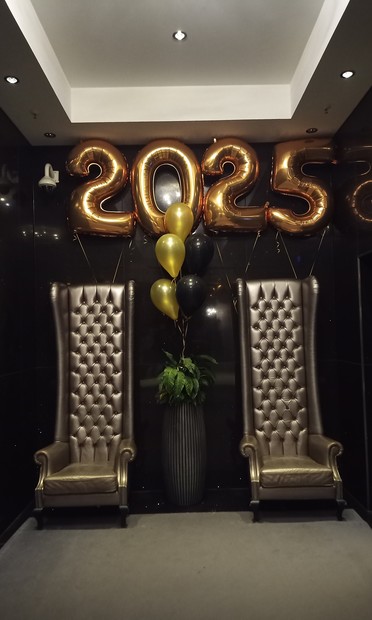 Sessel in der Hotellobby darüber hängen Luftballons mit 2025