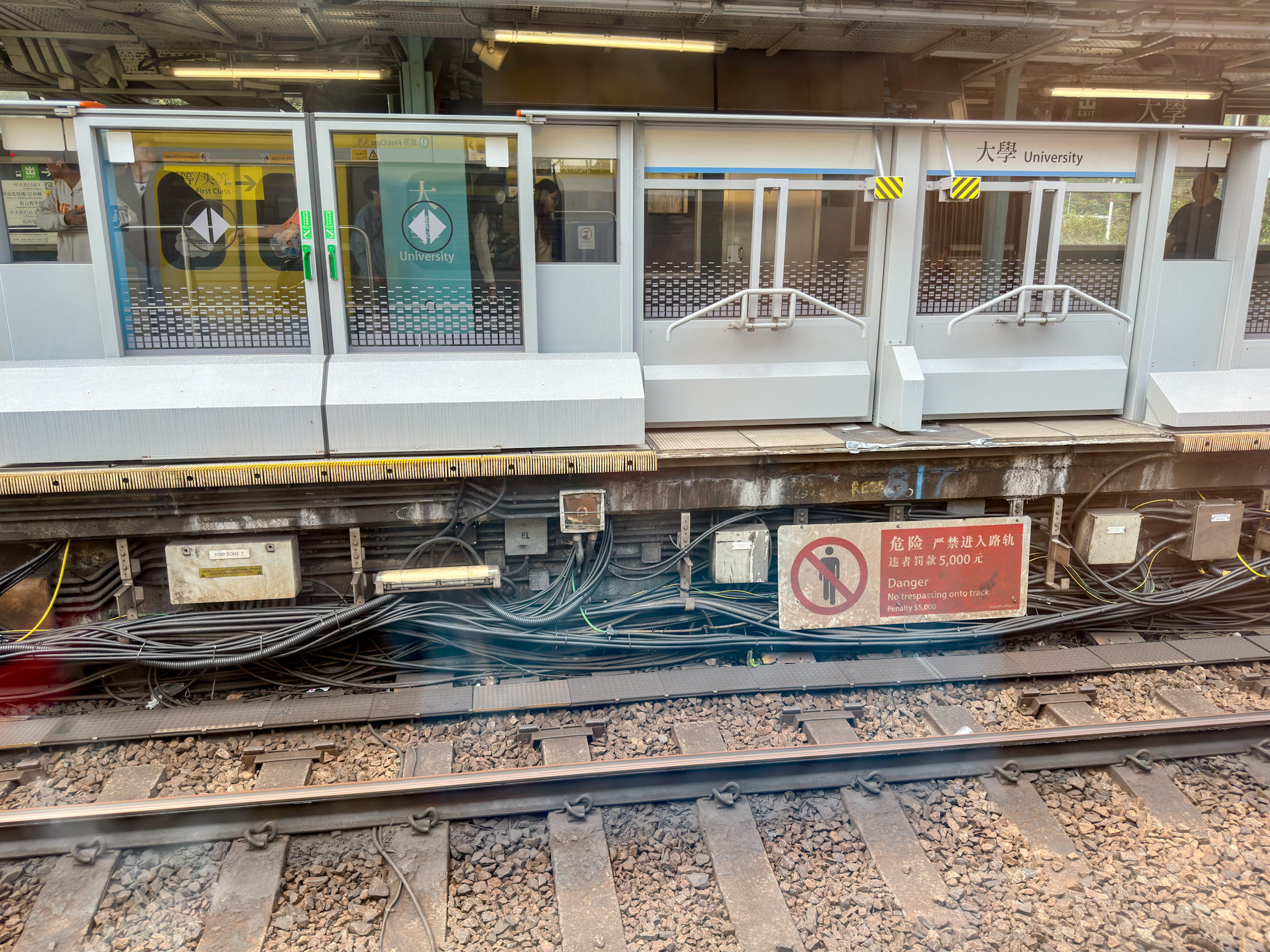 Blick aus dem Zug auf den Bahnsteig vom nebenliegenden Gleis. Man kann die Bahnsteigtüren dort quasi von der Zugseite sehen. 