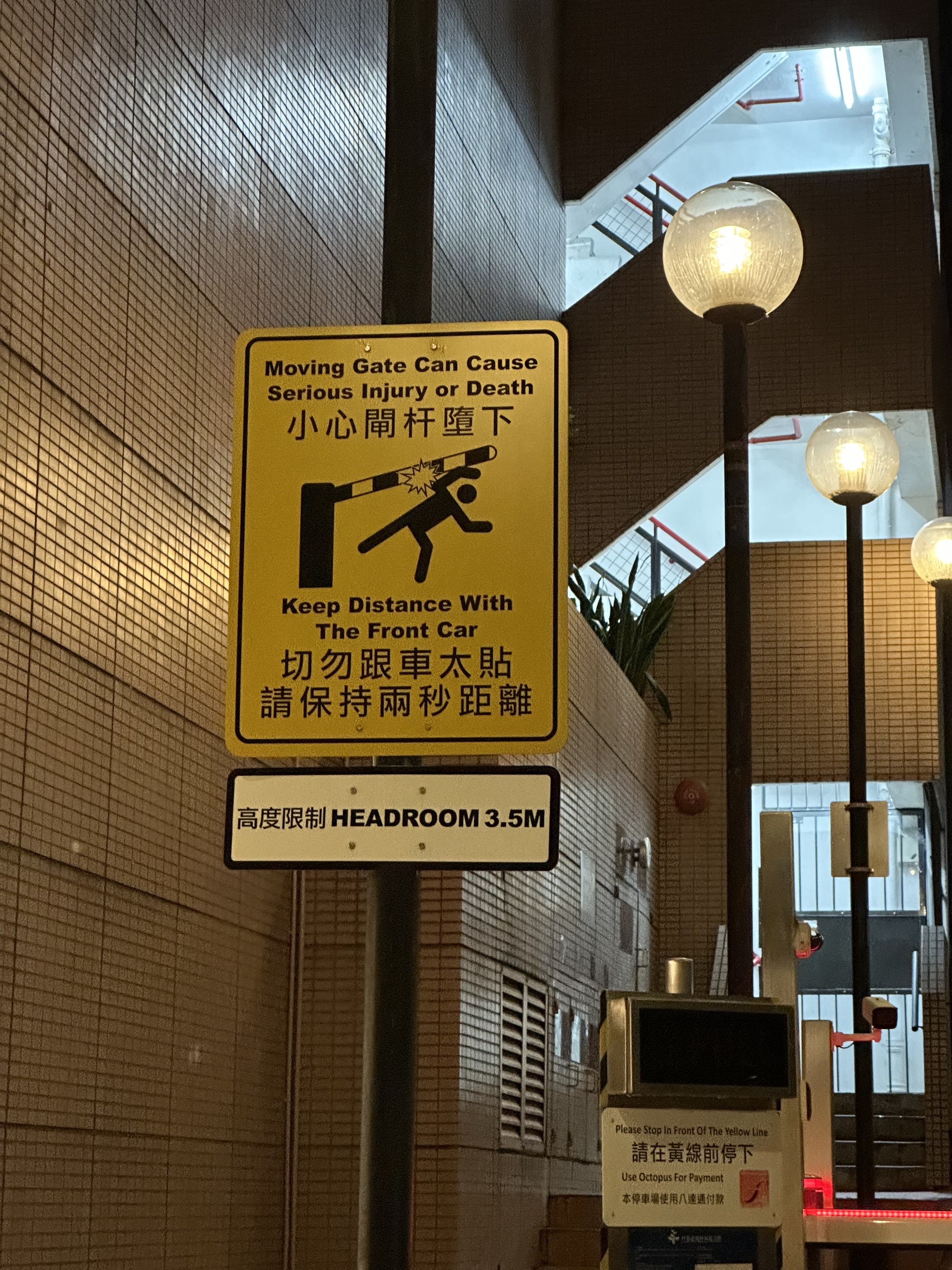 Ein Warnschild auf dem eine Schranke abgebildet ist, die ein Menschen erschlägt mit dem Text „Moving Gate Can Cause Serious Injury or Death“
