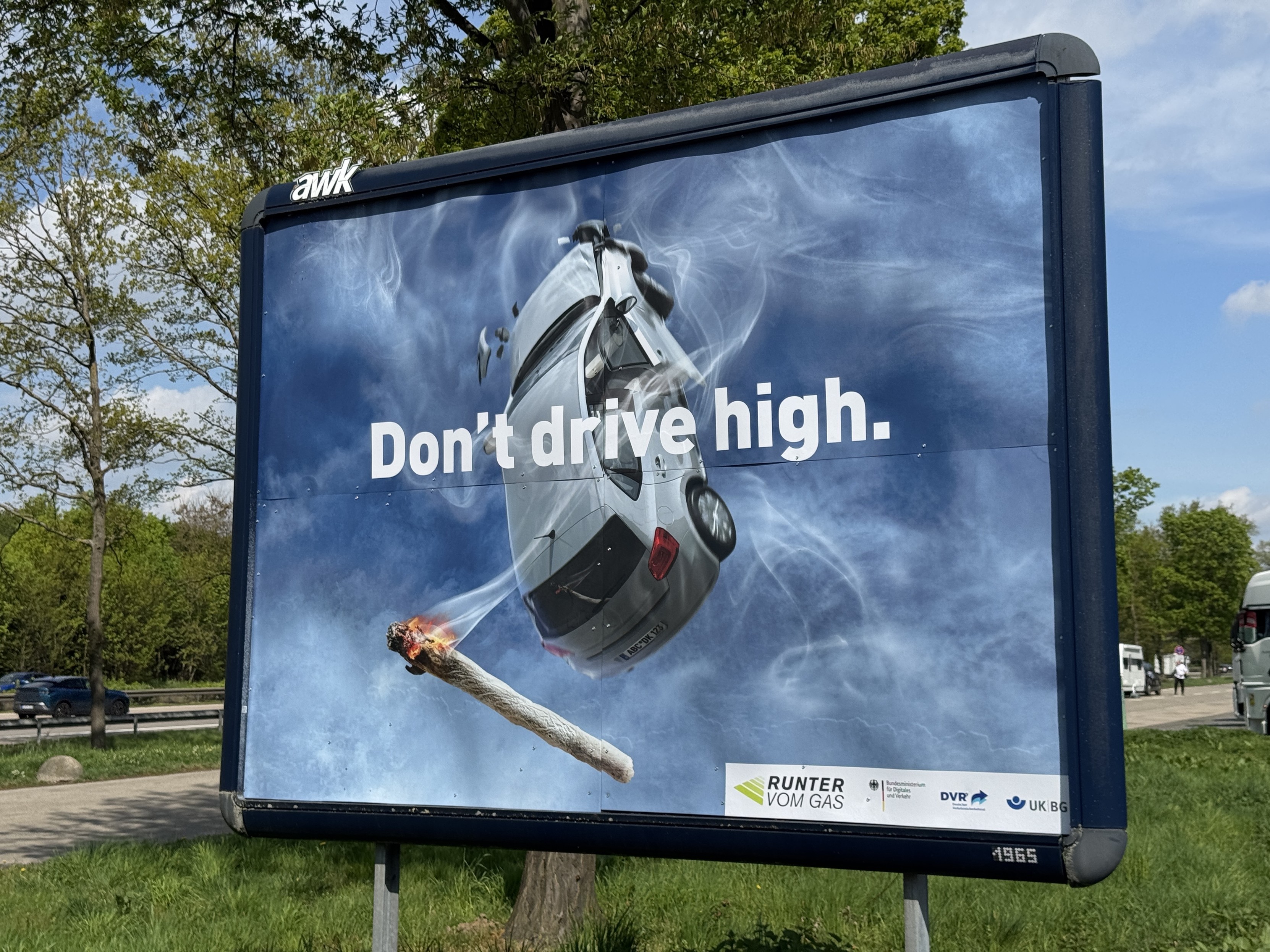 Werbeschild gegen Autofahren unter THC, ein Auto fliegt in den Himmel, davor ein Joint, Aufschrift „Don’t drive high“ und unten der slogan Runter vom Gas“