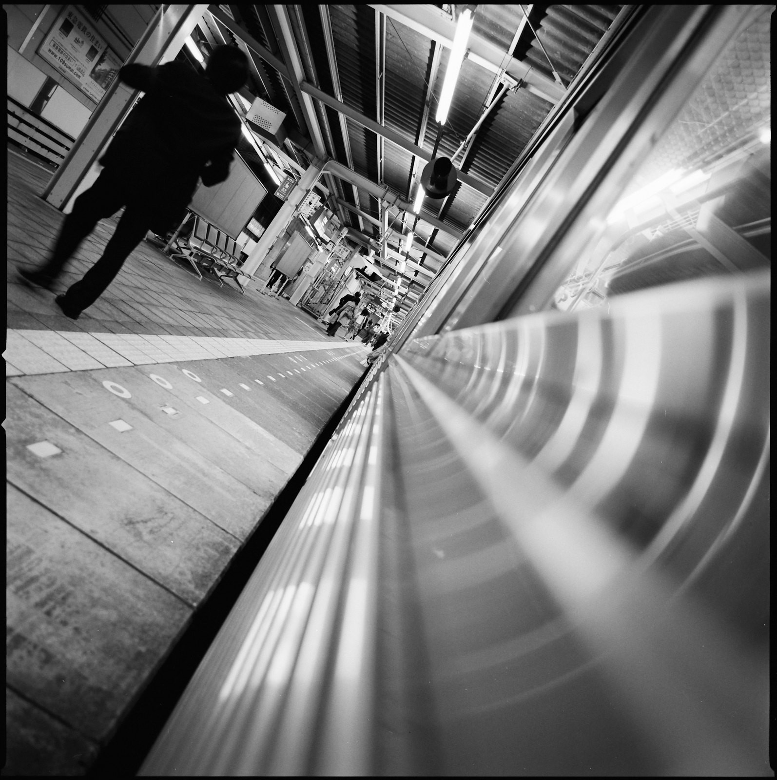 black and white photograph of a japanese salary man staggering as he exits a late night train. the frame is tilted at a disorienting angle. black and white photograph of a japanese salary man staggering as he exits a late night train. the frame is tilted at a disorienting angle.