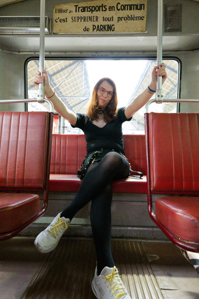 sarah, in an old tram carriage on the back seats, legs crossed