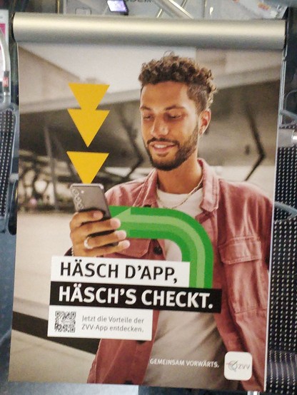 Analoge Werbetafel im Buss von der ZVV (Schweiz) – Man schaut auf sein Mobilephone (Handy) und darunter stehr: "Häsch d'App, häsch checkt."