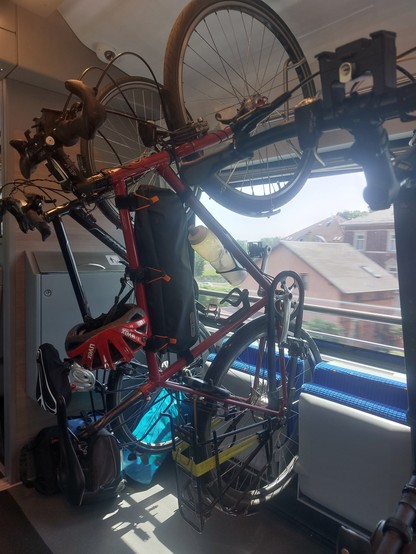 Im Zug hängen zwei Fahrräder senkrecht an der Decke. Durch das Fenster sieht man draußen ein Haus.