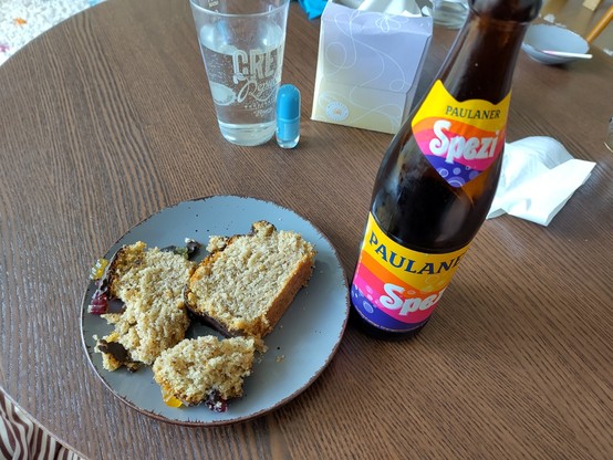 zu sehen ist ein grauer Teller mit 2 Stücken Nusskuchen mit Schokoüberzug und Gummibärchen oben drauf. daneben ein Spezi. im Hintergrund noch ein Glas Wasser. aber das war nicht gemeint .