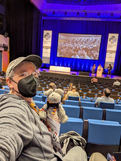 Selfie of me with plush donkey Timothy. Behind us the main stage of EuroPython 
