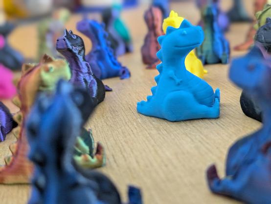 A close up shot on a light blue 3d printed chubby T-Rex in between all the other ones