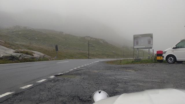 Blick durch Frontscheibe meiner Ente auf einen nebligen und nassen Flüelapass. Rechts im Bild ist die Front eines weißen VW-Campers zu sehen.