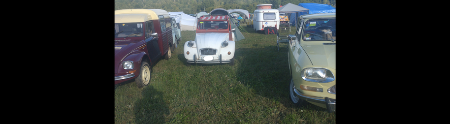 Meine rot-weiße Ente steht mit rot-weiß gestreiftem Sonnendach über den Vordersitzen zwischen einer weinroten Acadiane mit beigem Dach und einem senfgelben Ami 8. Im Hintergrund viele weiter 2CV, 2CV-Derivat, alte kleine Wohnwägen und sehr viele Zelte.