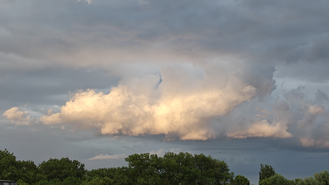 Eine hell angeleuchtete Wolke zwischen grauen Gewitterwolken.